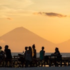 Tourists in the restaurant on Gili Travangan island enjoying evening sunset view on Gunung Agung volcano on Bali, Indonesia.; Shutterstock ID 403456900; your: Claire N; gl: 65050; netsuite: Online Ed; full: Gili Islands update