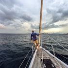 Rear view shot of single white man standing on bow of yacht looking out across Lombok, Indonesia