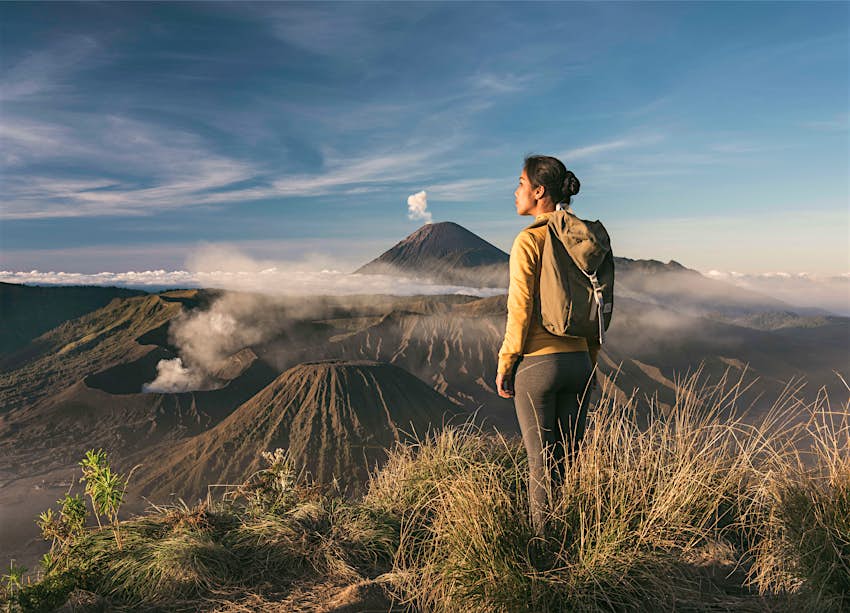 Asian woman standing in front of Mt Bromo and Mt Semeru, admiring the view at sunrise