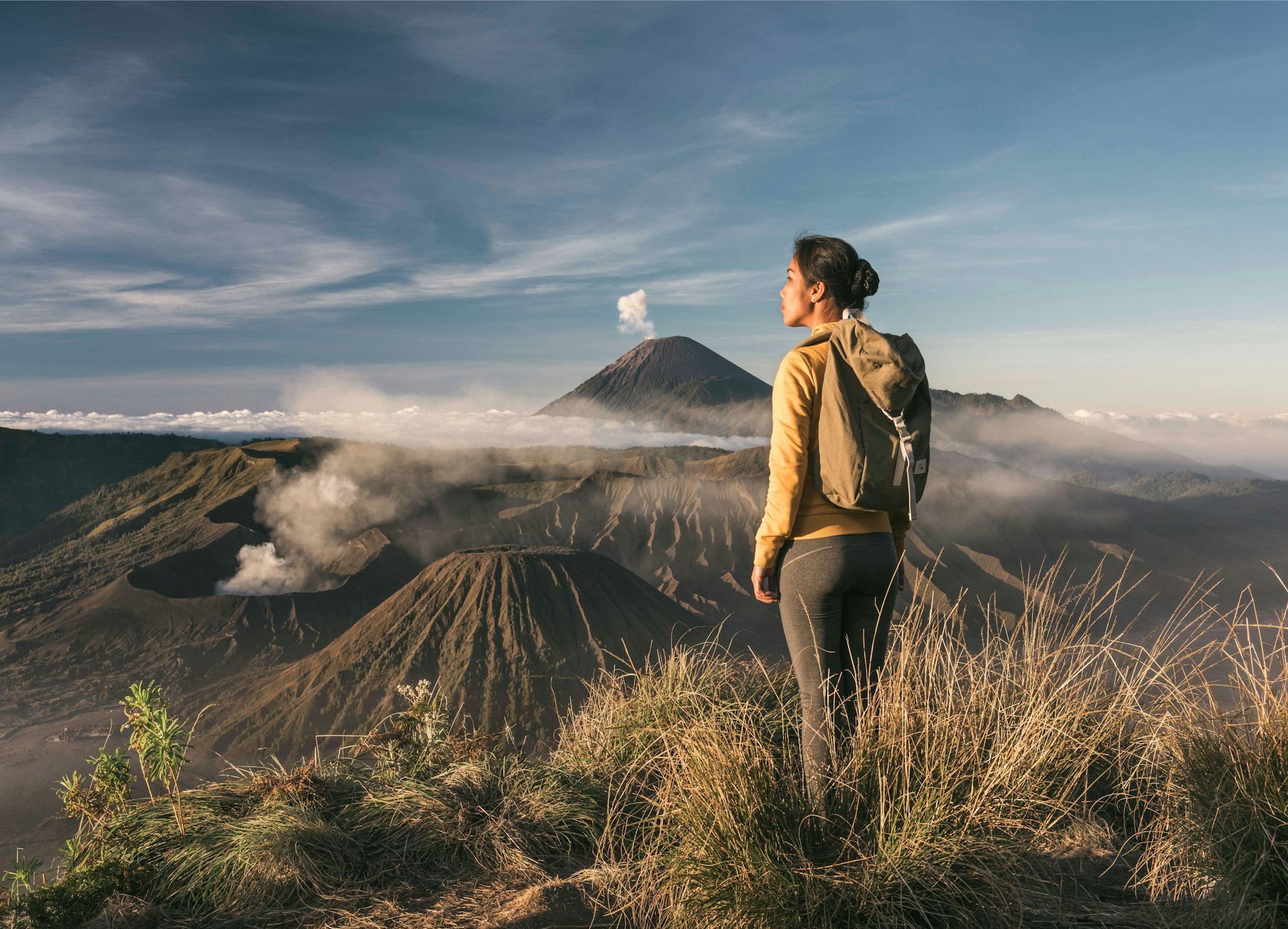 Asian woman standing in front of Mt Bromo and Mt Semeru, admiring the view at sunrise