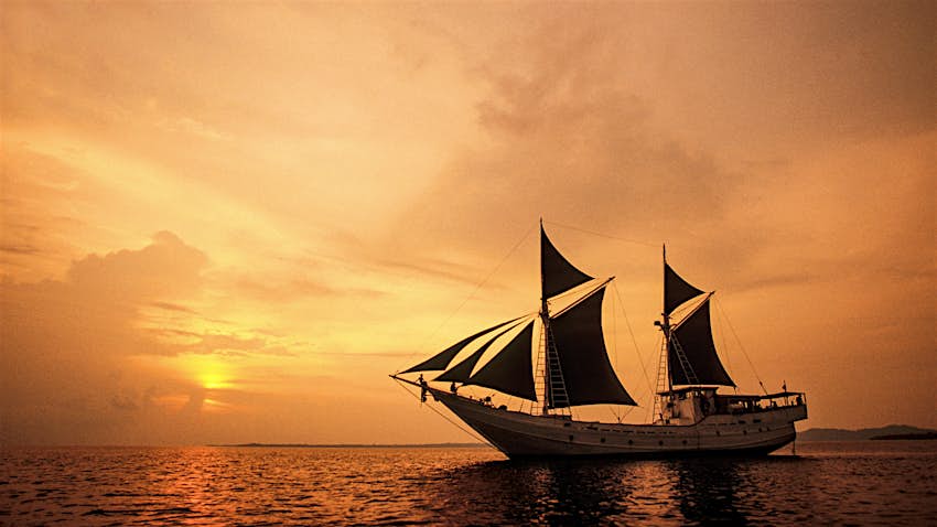 Sekunar Phinisi gaya Bugis berlayar di Kepulauan Mentawai saat matahari terbenam di Indonesia