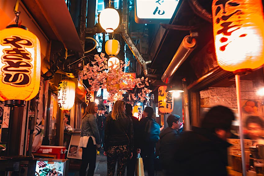Shinjuku bar street, Tokyo A dark, narrow alley lined with bars and lots of blurry figures moving around