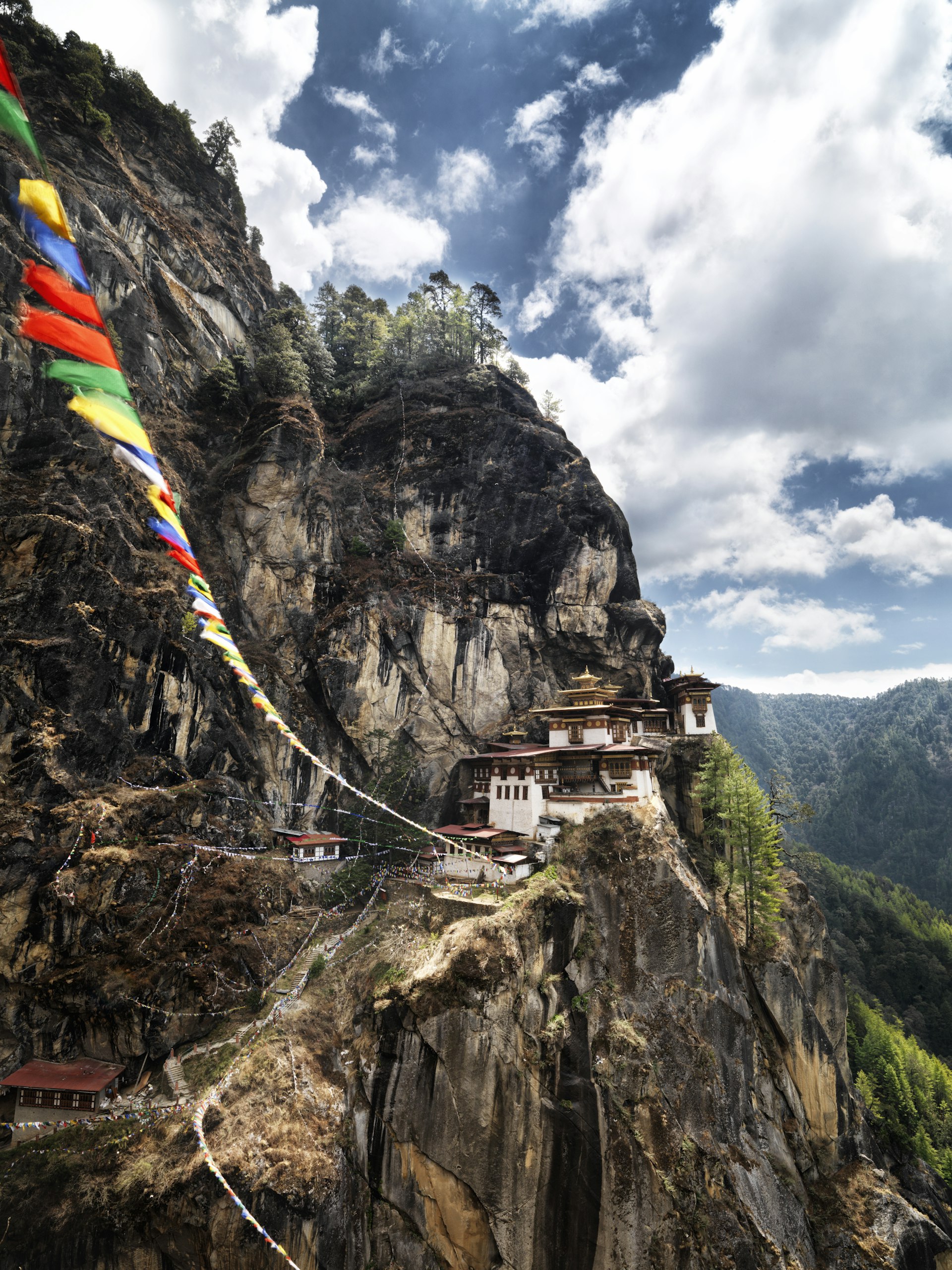 Prayer flags leading to Taktshang Goemba (Tiger’s Nest) monastery on mountain ridge.