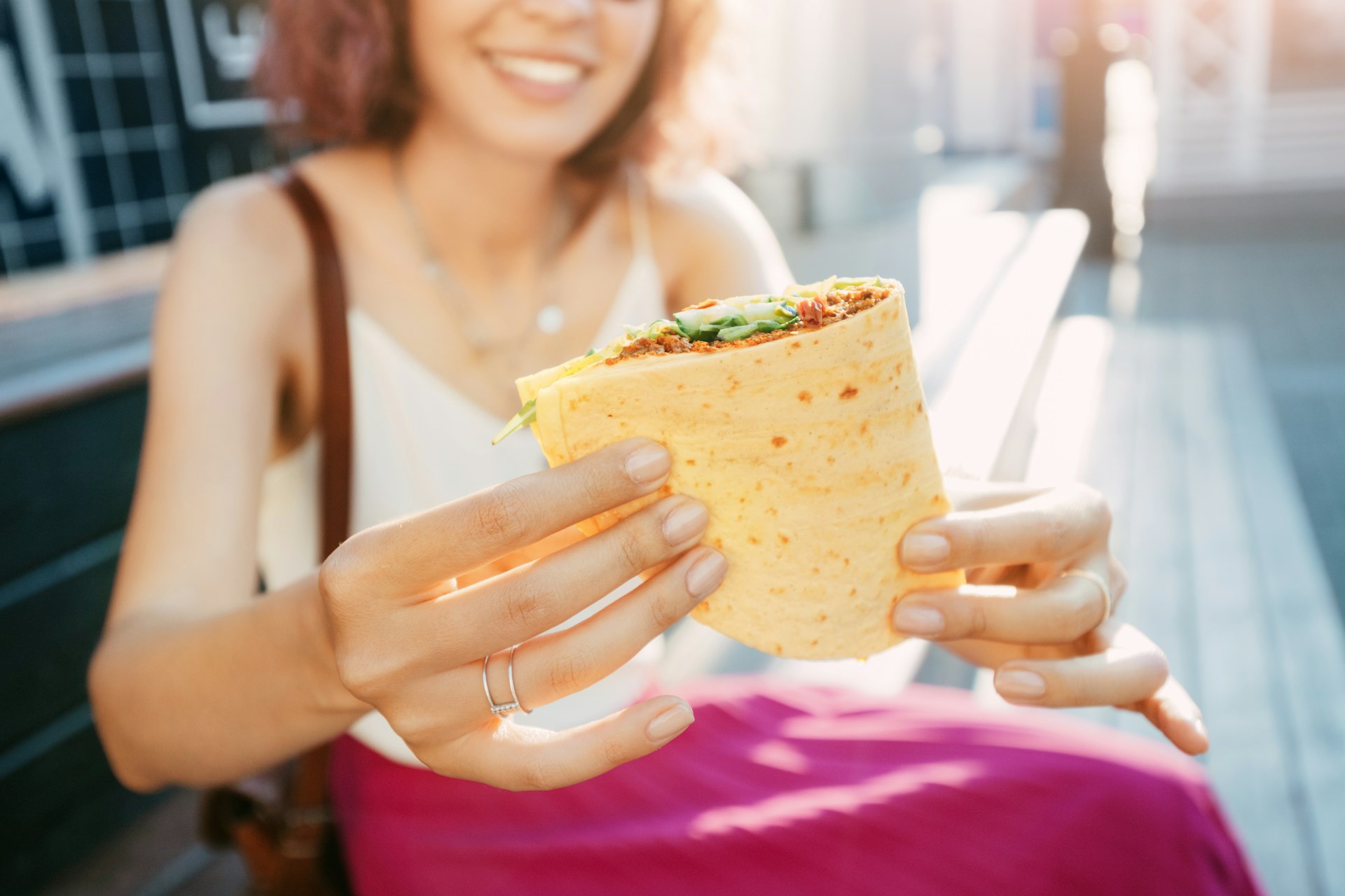 A woman holds out a Mexican quesadilla towards the camera - a folded bread stuffed with fillings