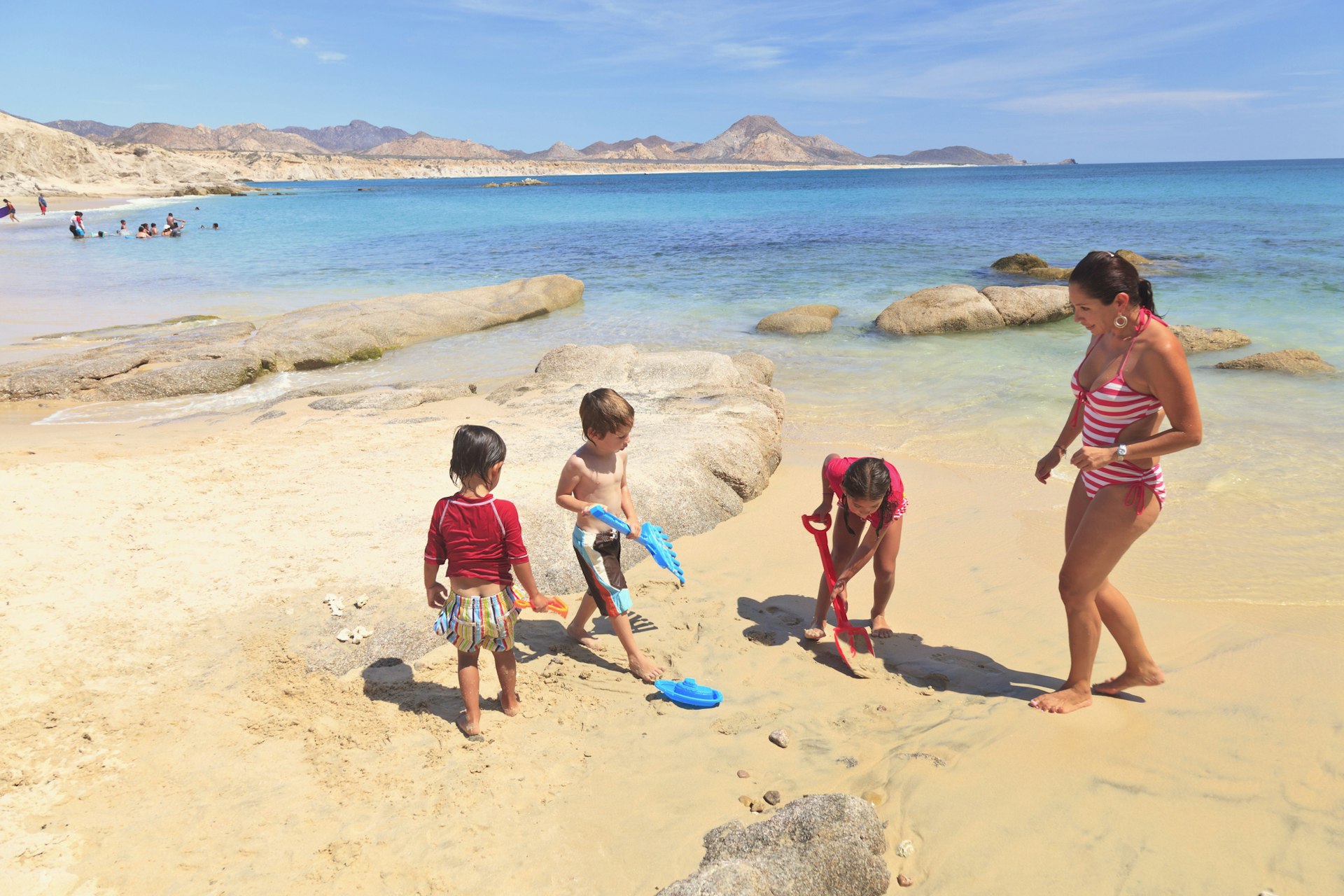 A Mother Plays With Her Three Children On A Beach