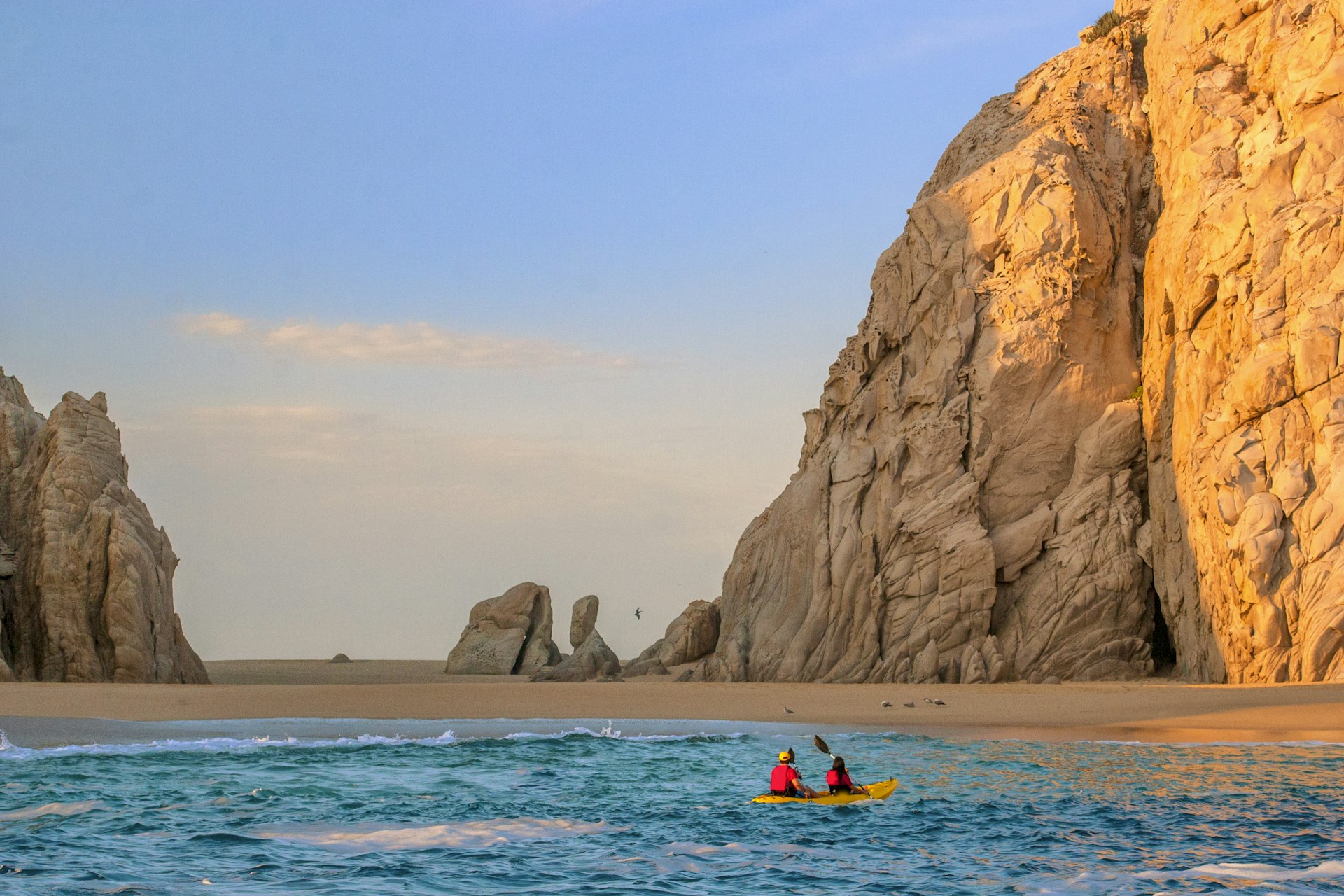 Two people in a kayak paddle towards Lover's Beach in Los Cabos