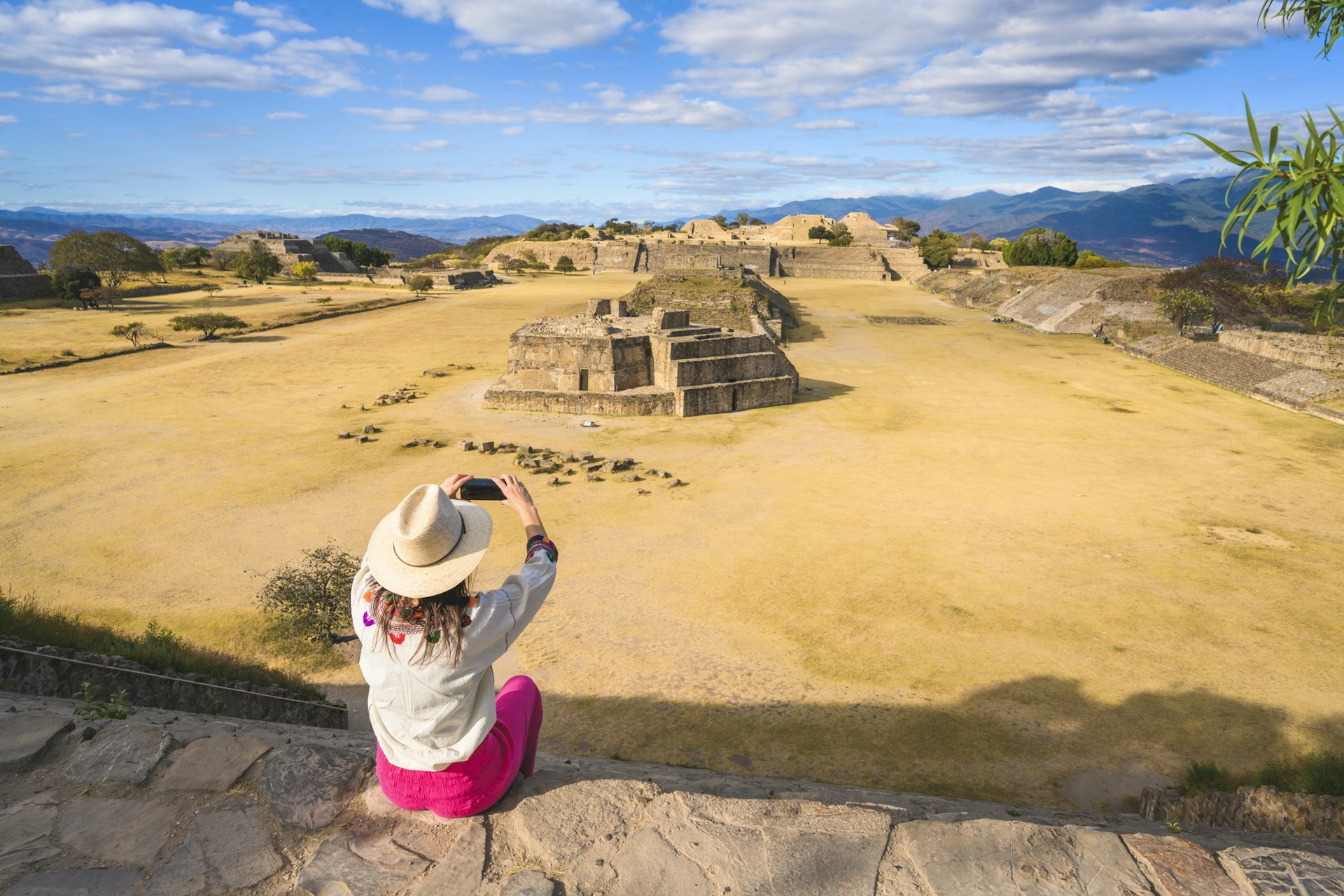 A woman sits at a high point above Monte Albán, an archaeological site in Oaxaca, Mexico
