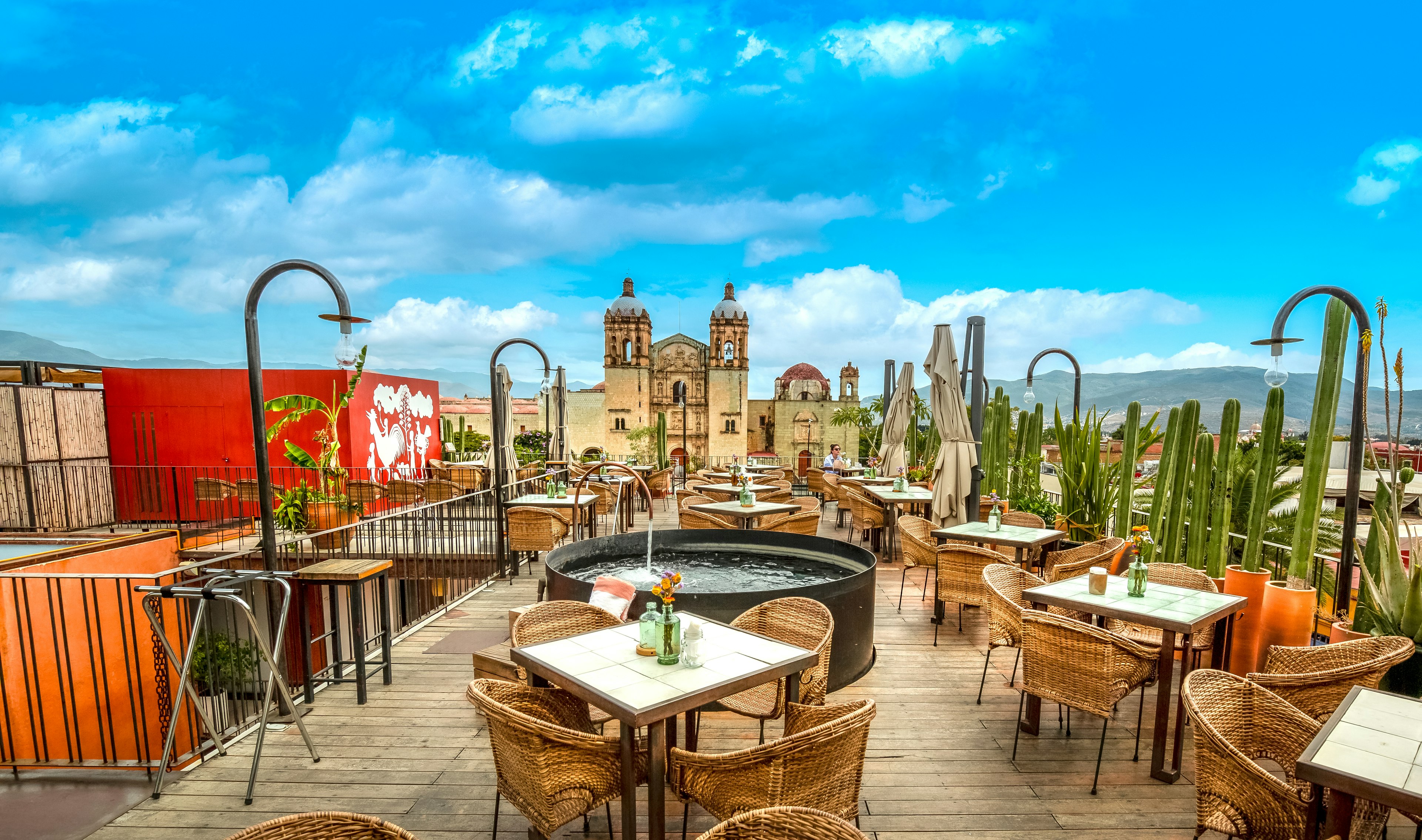 An empty outdoors restaurant with tables and chairs overlooked by a hugh church building