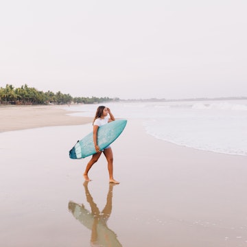 Mexico, Guerrero, Zihuantanejo - March 29, 2021: Young female surfer of Mexican ethnicity on the beach of Playa Blanca.