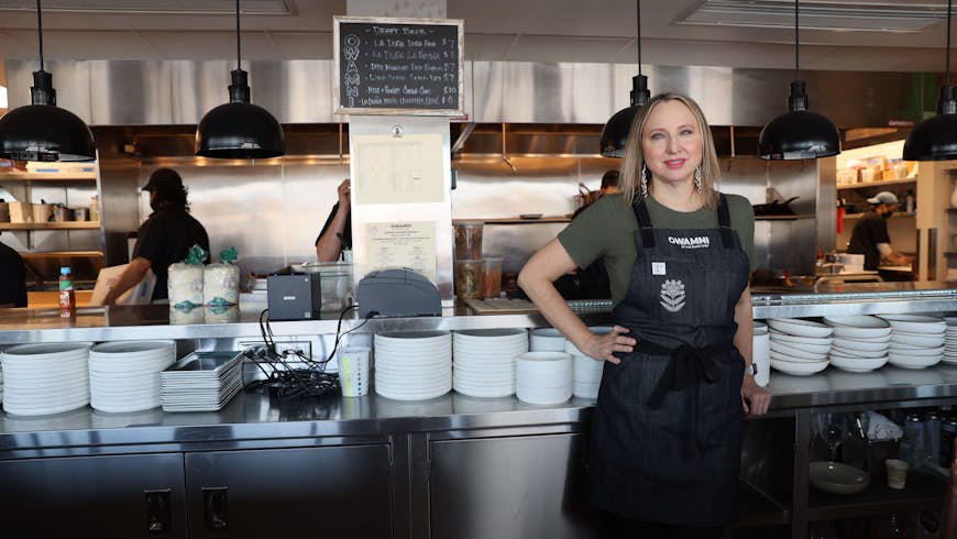 Dana Thompson stands in the Owamni by The Sioux Chef kitchen with staff 
