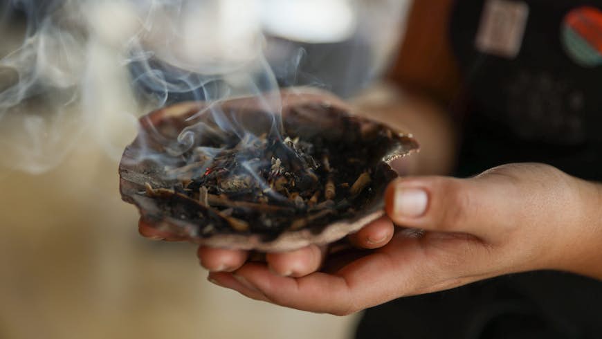 Smudging the restaurant Owamni by The Sioux Chef with sage from a shell