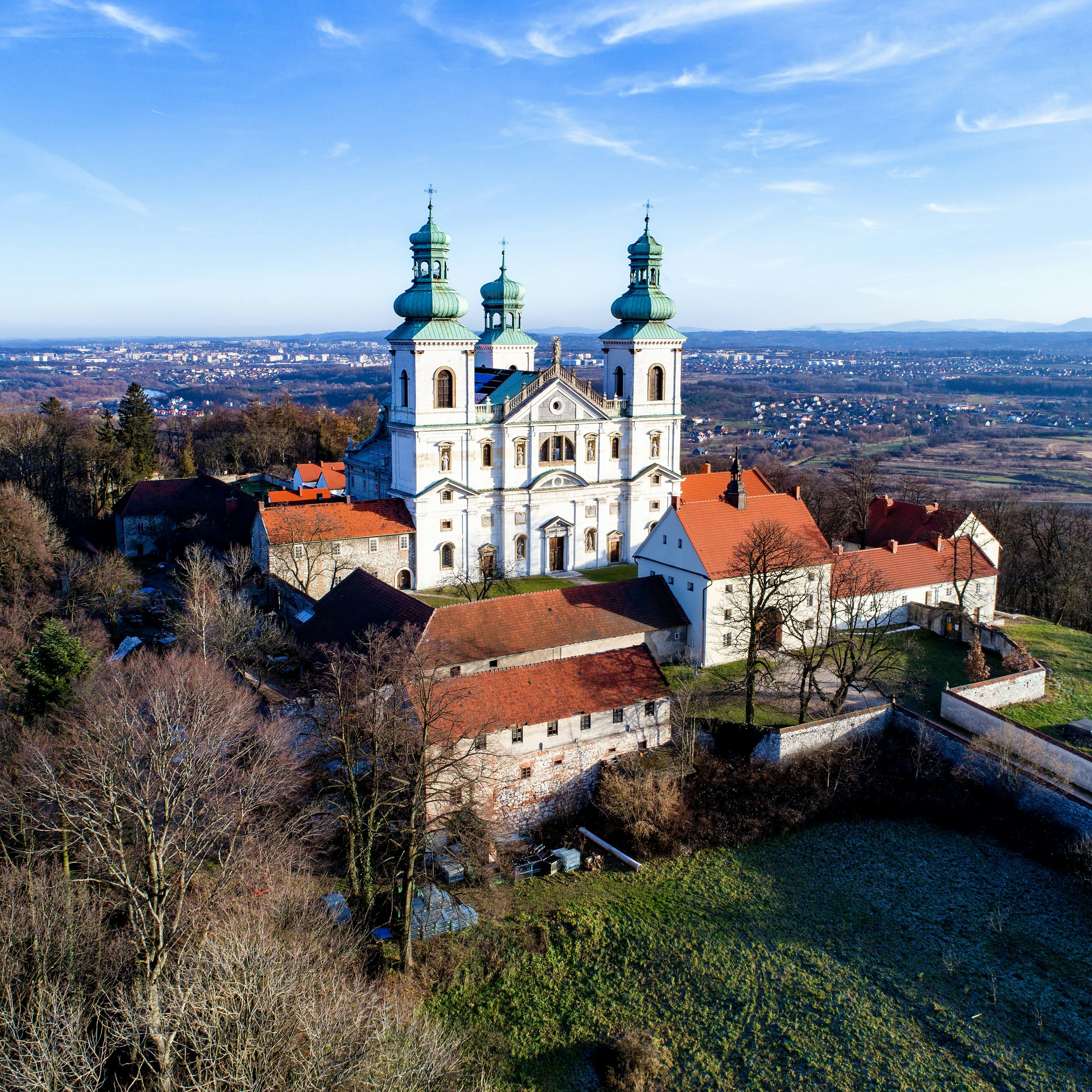 Camaldolese monastery and baroque church in the wood on the hill in Bielany, Krakow, Poland , Aerial view in winter with Vistula River and far view of Cracow city in the background