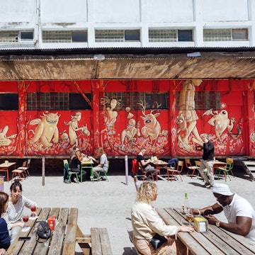 People meeting and drinking beverages at outdoor restaurant in urban city area with trendy shops and cafes - stock photo