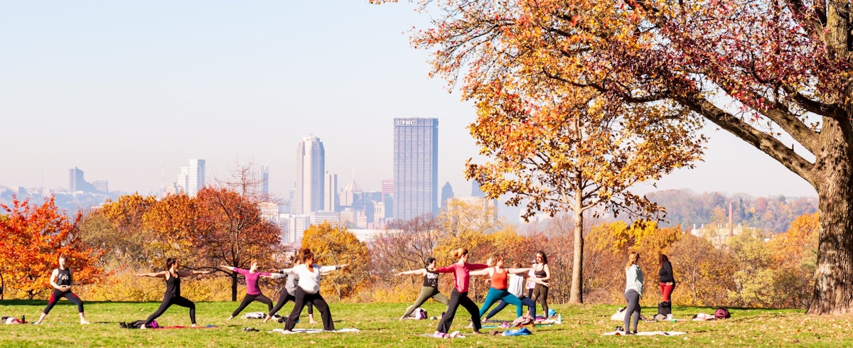 Pittsburgh, Pennsylvania, USA 11/7/20 A group of women having a yoga class in Schenley Park with downtown Pittsburgh in the background on a hazy fall morning