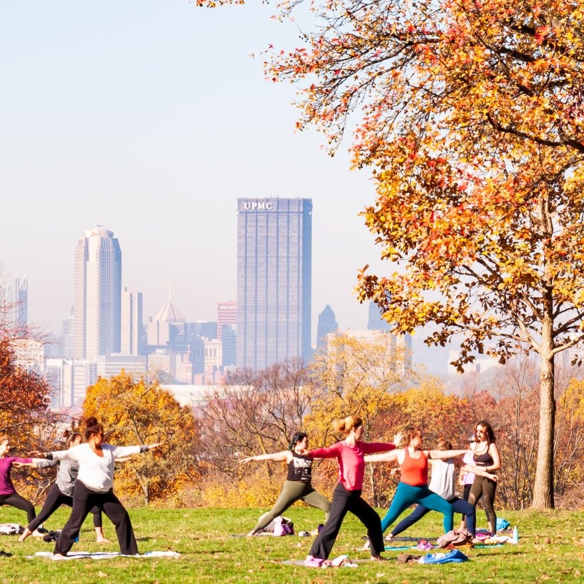 Pittsburgh, Pennsylvania, USA 11/7/20 A group of women having a yoga class in Schenley Park with downtown Pittsburgh in the background on a hazy fall morning