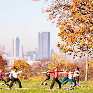 Pittsburgh, Pennsylvania, USA 11/7/20 A group of women having a yoga class in Schenley Park with downtown Pittsburgh in the background on a hazy fall morning