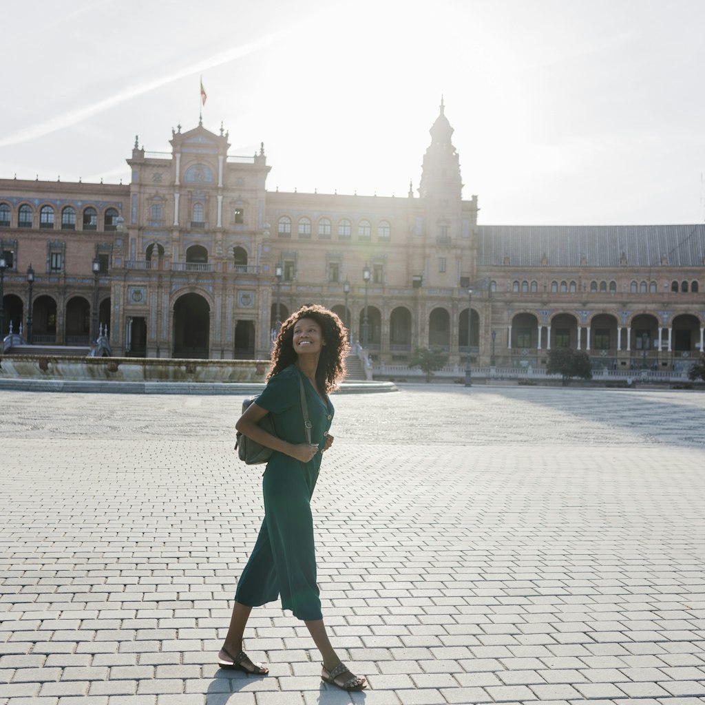 Smiling young woman looking away while walking at Plaza De Espana, Seville, Spain