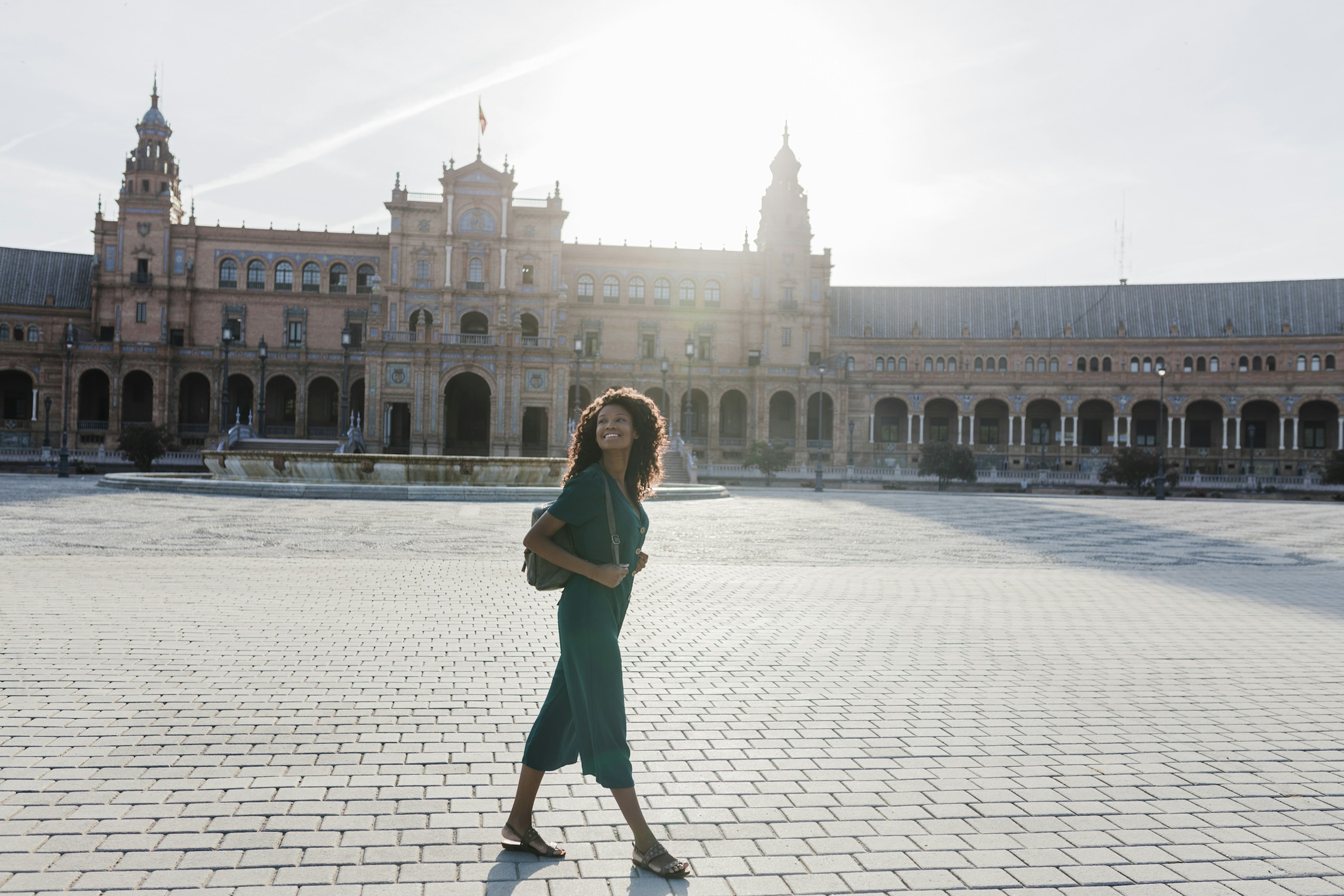 Smiling young woman looking away while walking at Plaza De Espana, Seville, Spain