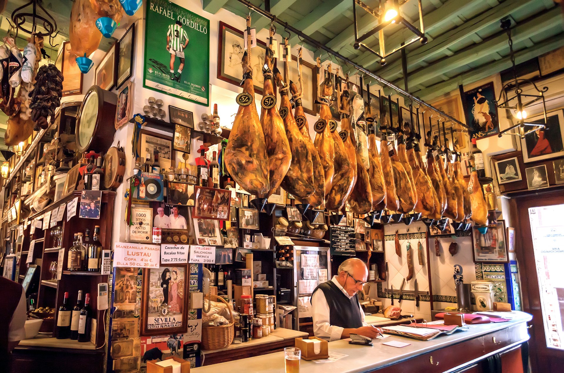 The interior of a traditional tapas bar in Seville with legs of jamon ham hanging around the bar