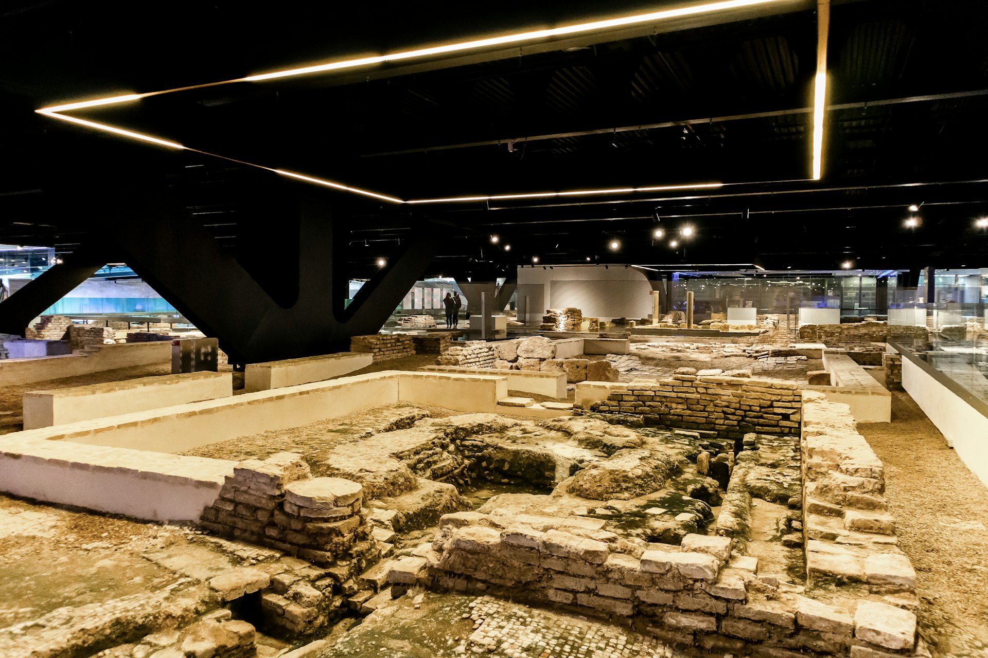An archaeological museum with ruins lining the ground and visitors looking on from walkways
