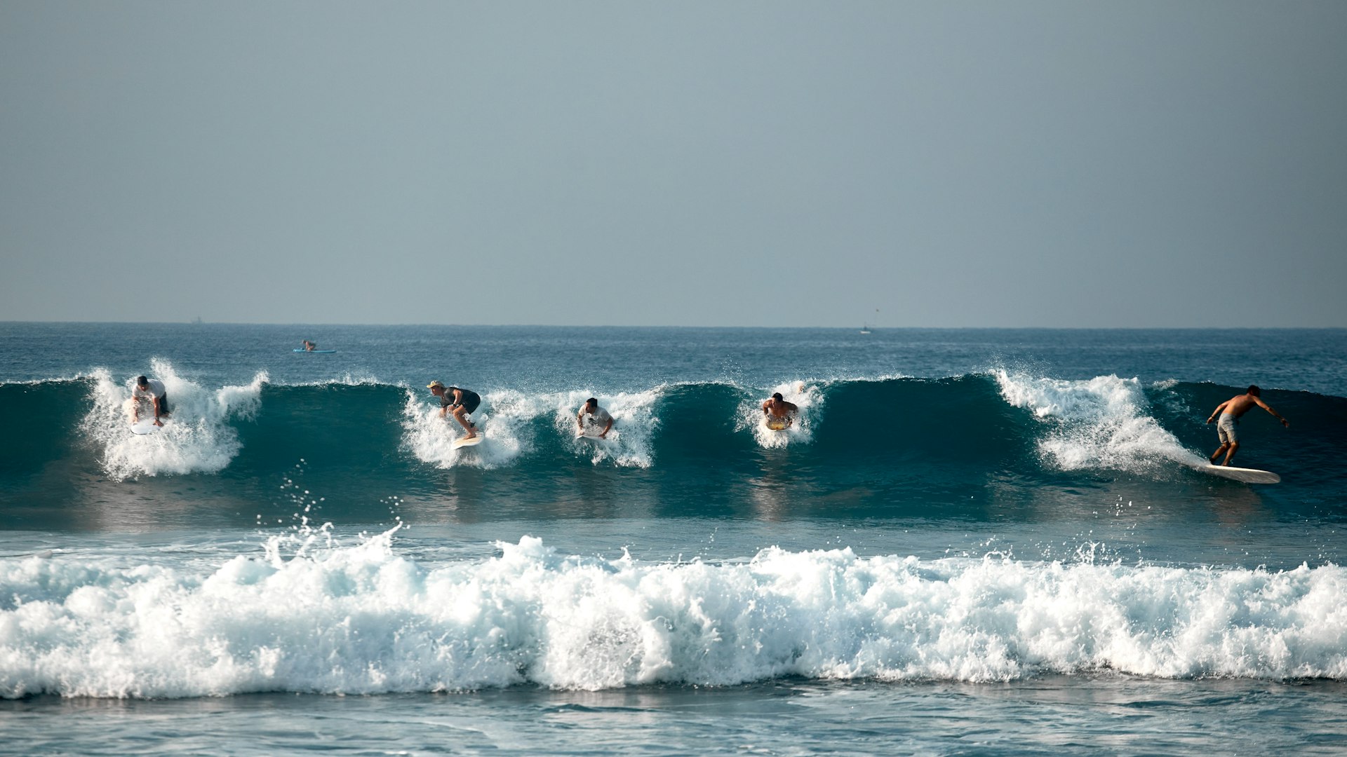Five surfers in a row catch a wave in a tropical destination