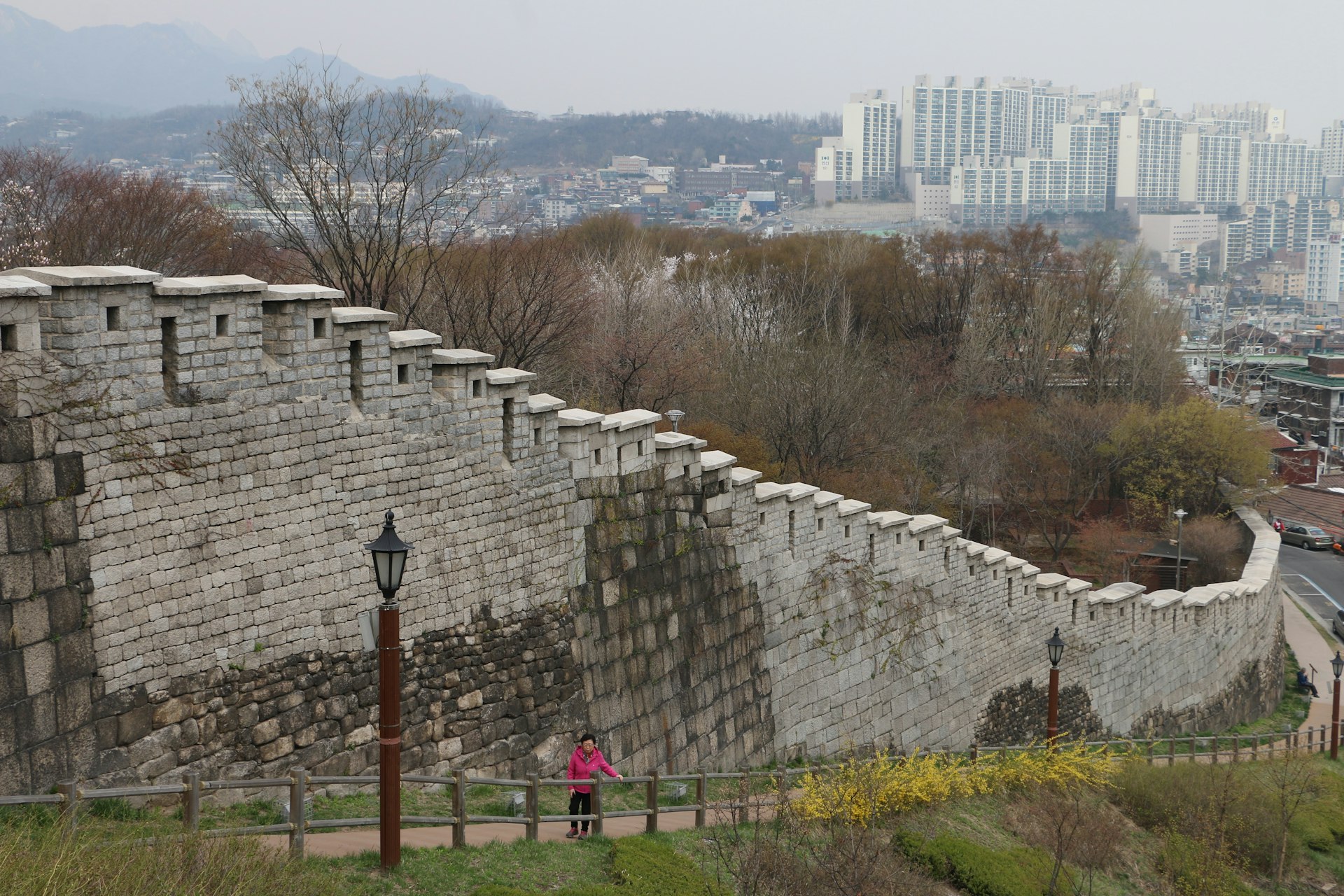 The old Seoul city walls with the skyline of Seoul in the distance, along a path in Naksan Park