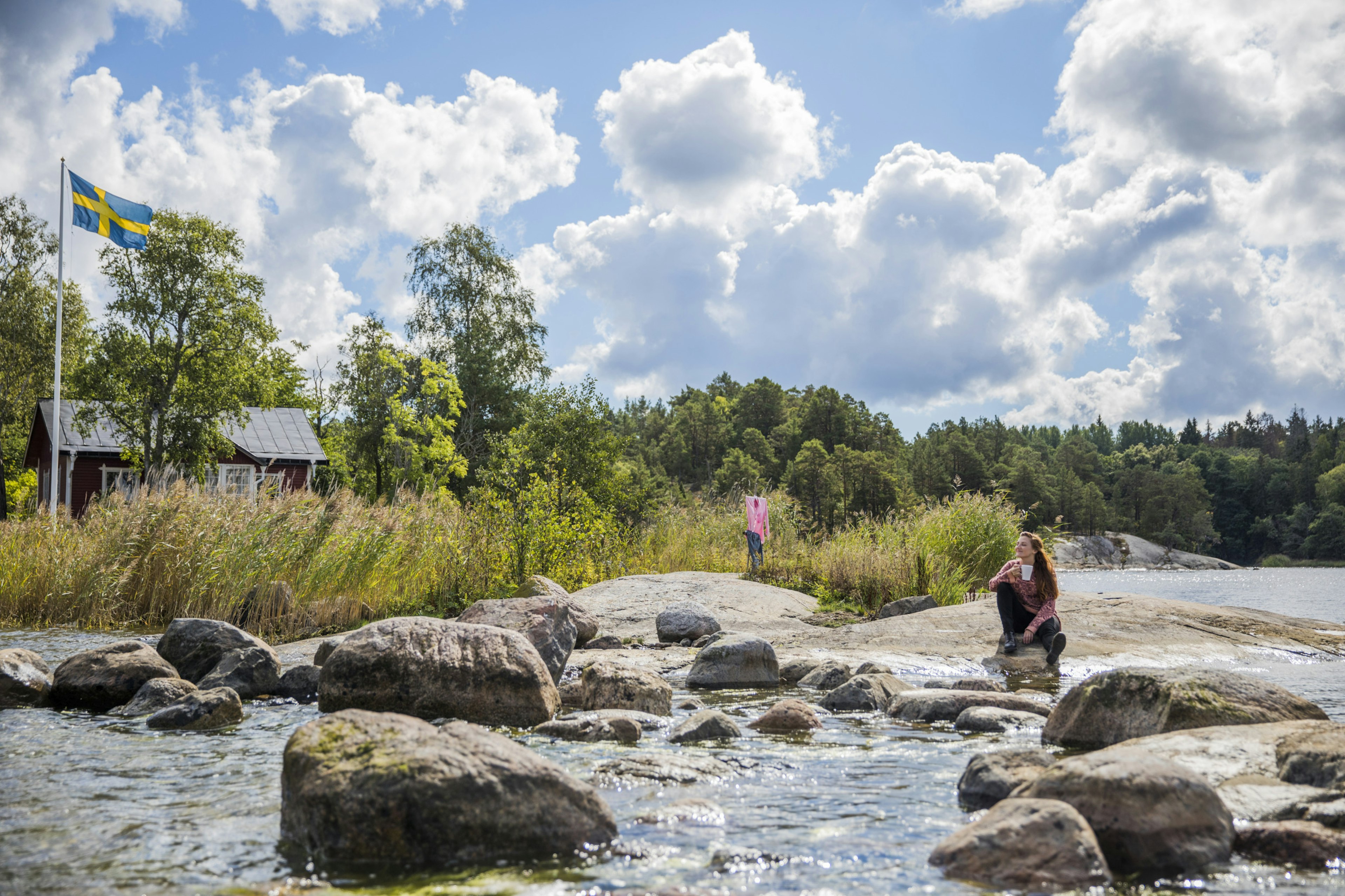 Woman sitting next to river on sunny day in Stockholm