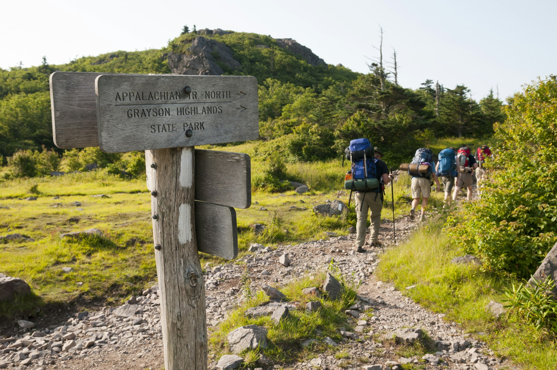 Hikers with full backpacks walk along a trail signposted Appalachian Trail North