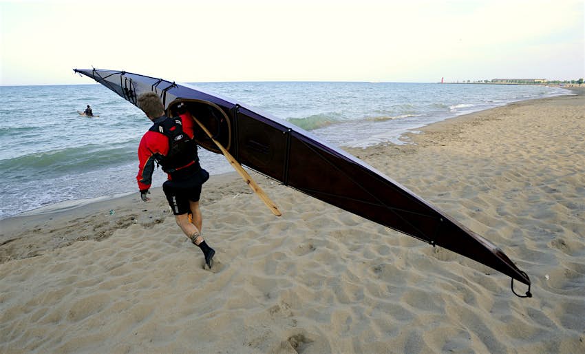 Person carrying a kayak on their shoulder, accessing the Lake Michigan water trail from a beach, Kenosha, Wisconsin