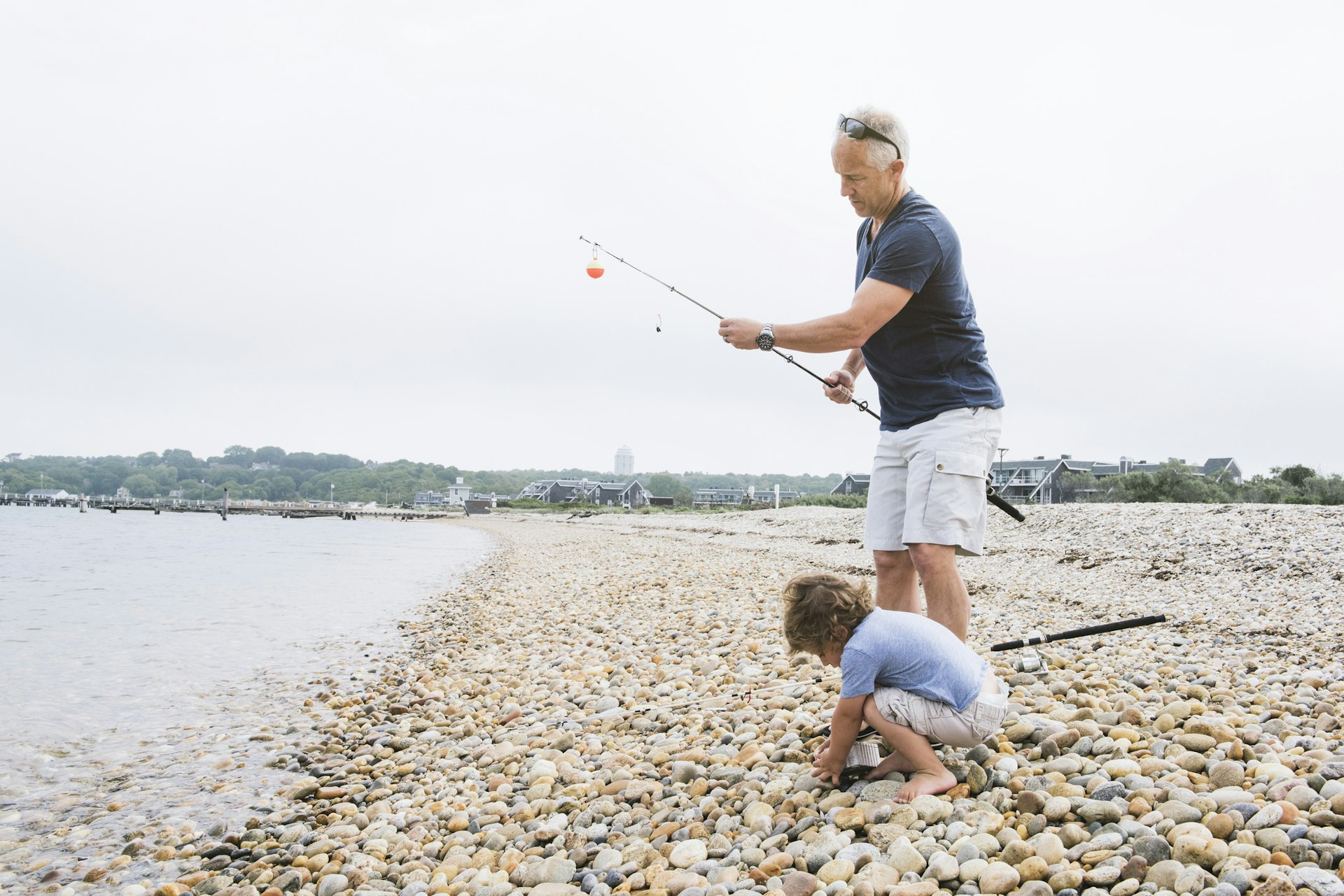 Father and son fishing at a pebbly beach