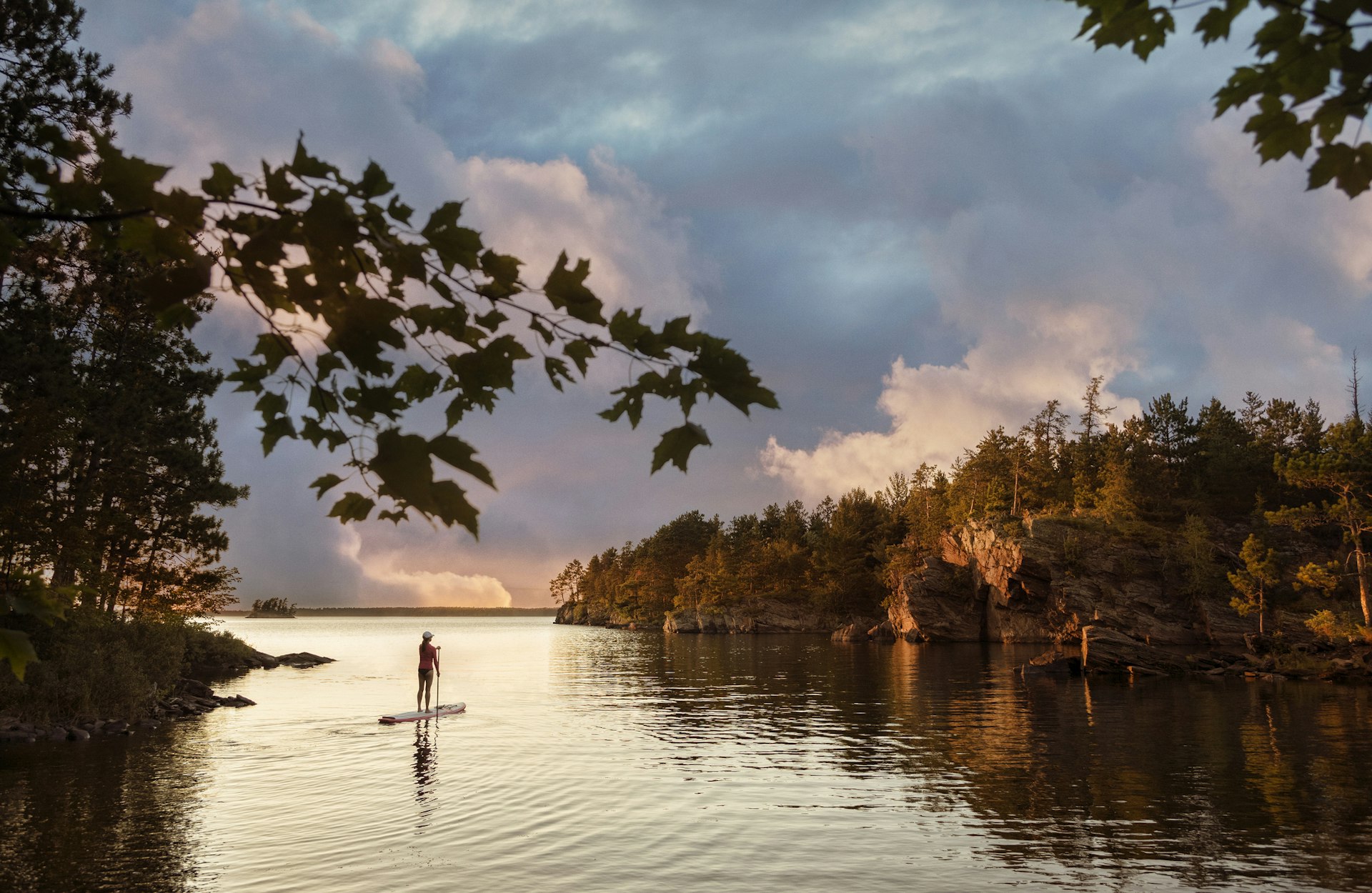 A woman stands on a paddleboard at sunset at Voyageurs National Park, Minnesota