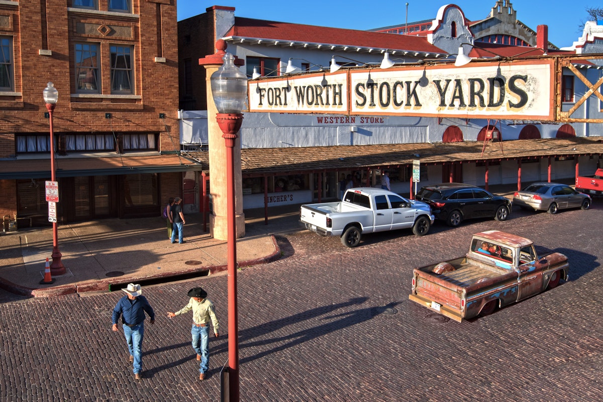 Rodeo cowboys and a low rider truck on Exchange Street in the Fort Worth Stockyards Historic District.  The district is listed on the National Register of Historic Places.