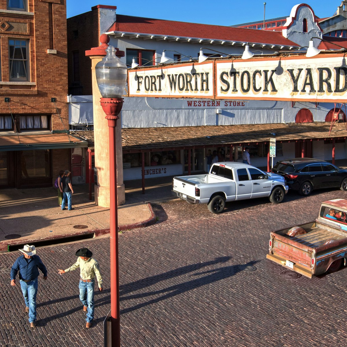 Rodeo cowboys and a low rider truck on Exchange Street in the Fort Worth Stockyards Historic District.  The district is listed on the National Register of Historic Places.