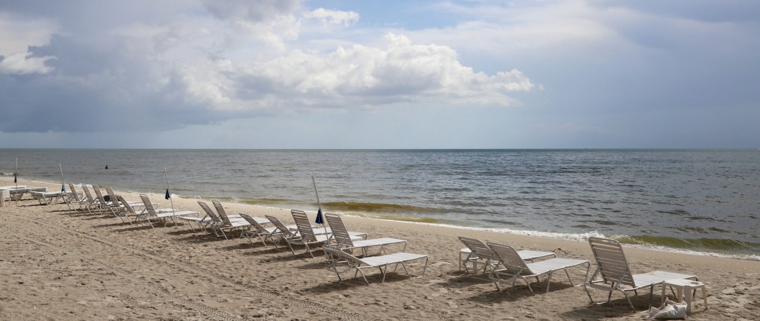 Row of lounge chairs on a scenic ocean beach, Delnor-Wiggins Pass State Park, Naples, Florida, USA - stock photo
