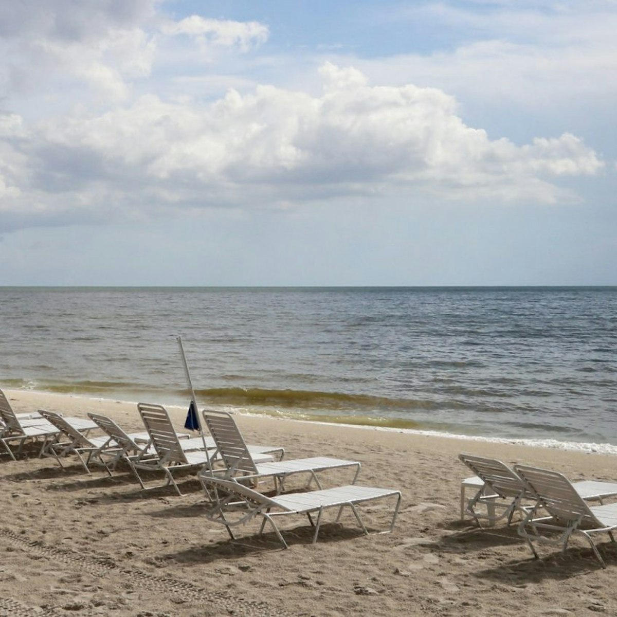 Row of lounge chairs on a scenic ocean beach, Delnor-Wiggins Pass State Park, Naples, Florida, USA - stock photo
