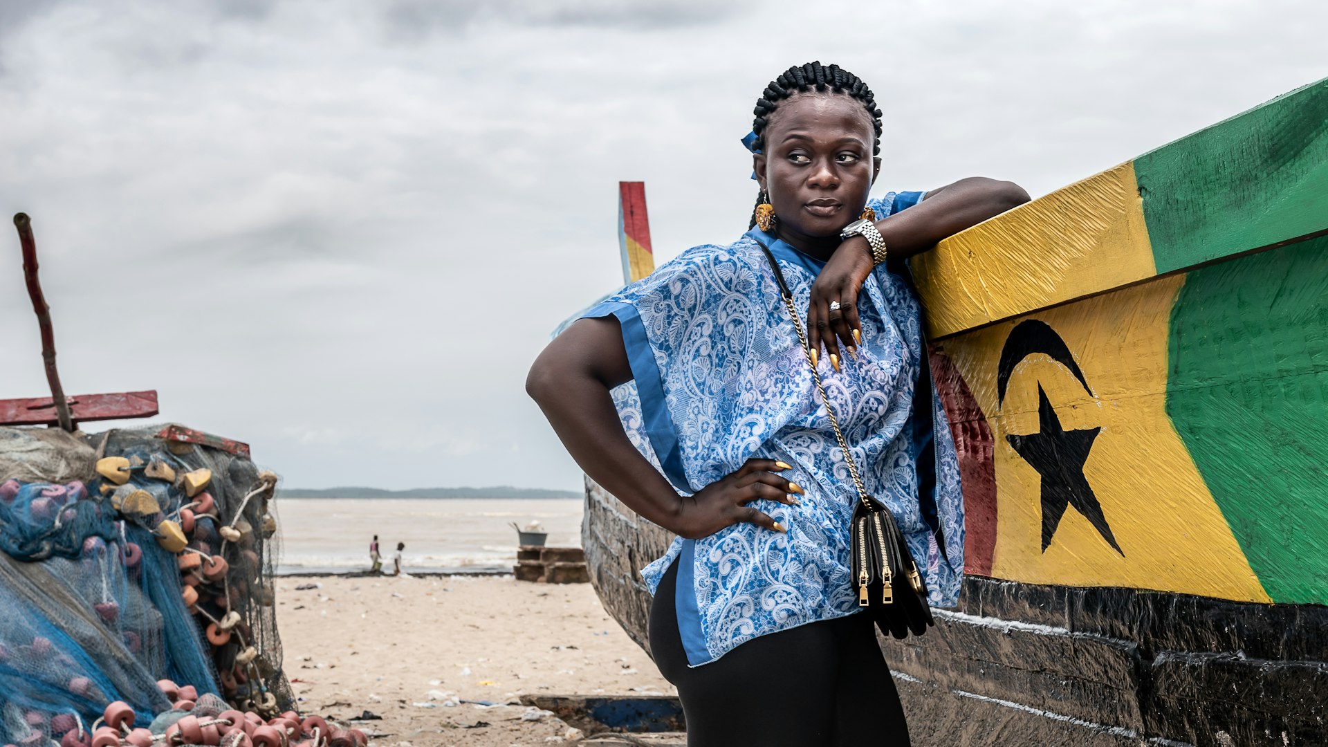 A woman stands by a fishing boat on one of the beaches in Ghana