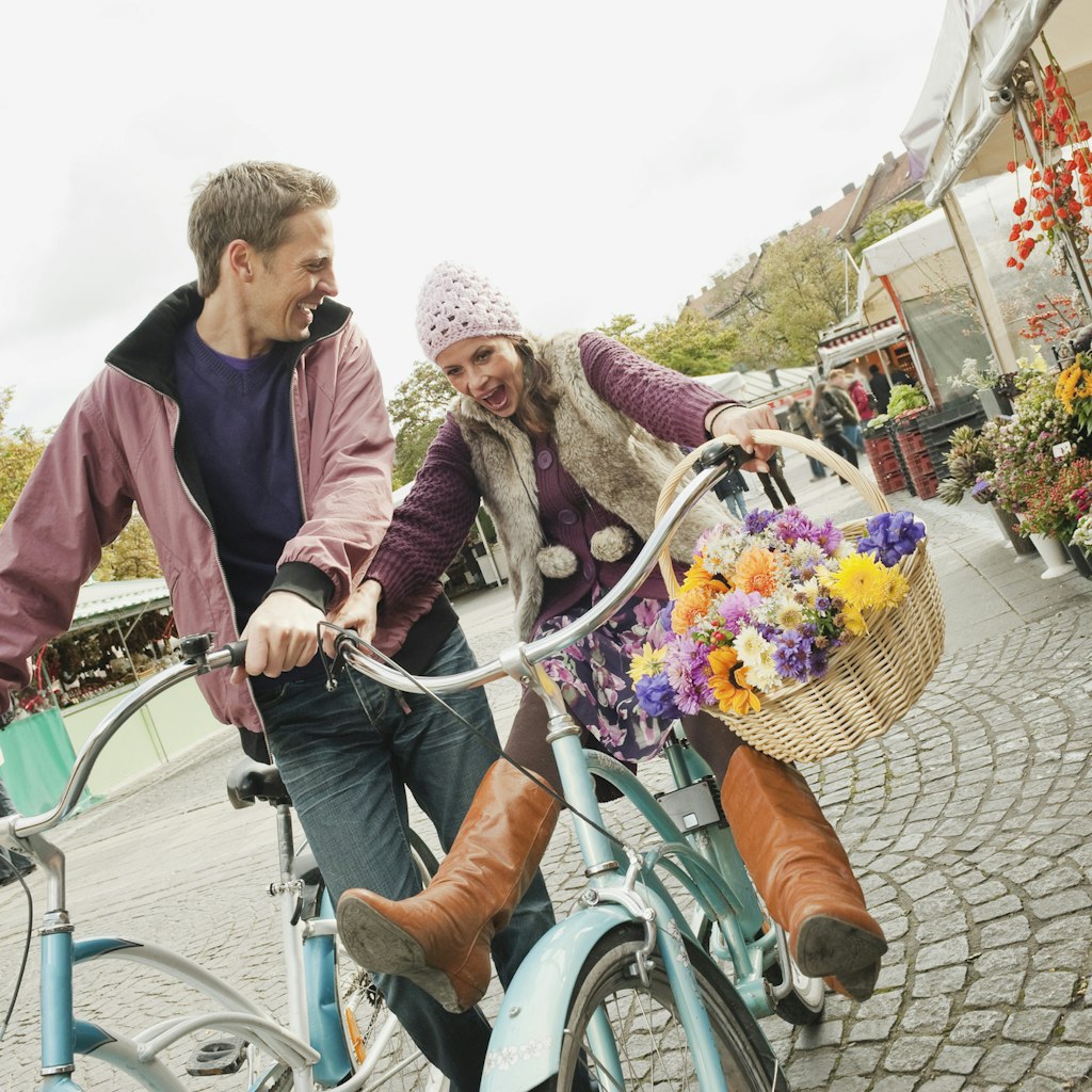 Germany, Bavaria, Munich, Viktualienmarkt, Couple with bicycles, laughing, portrait 