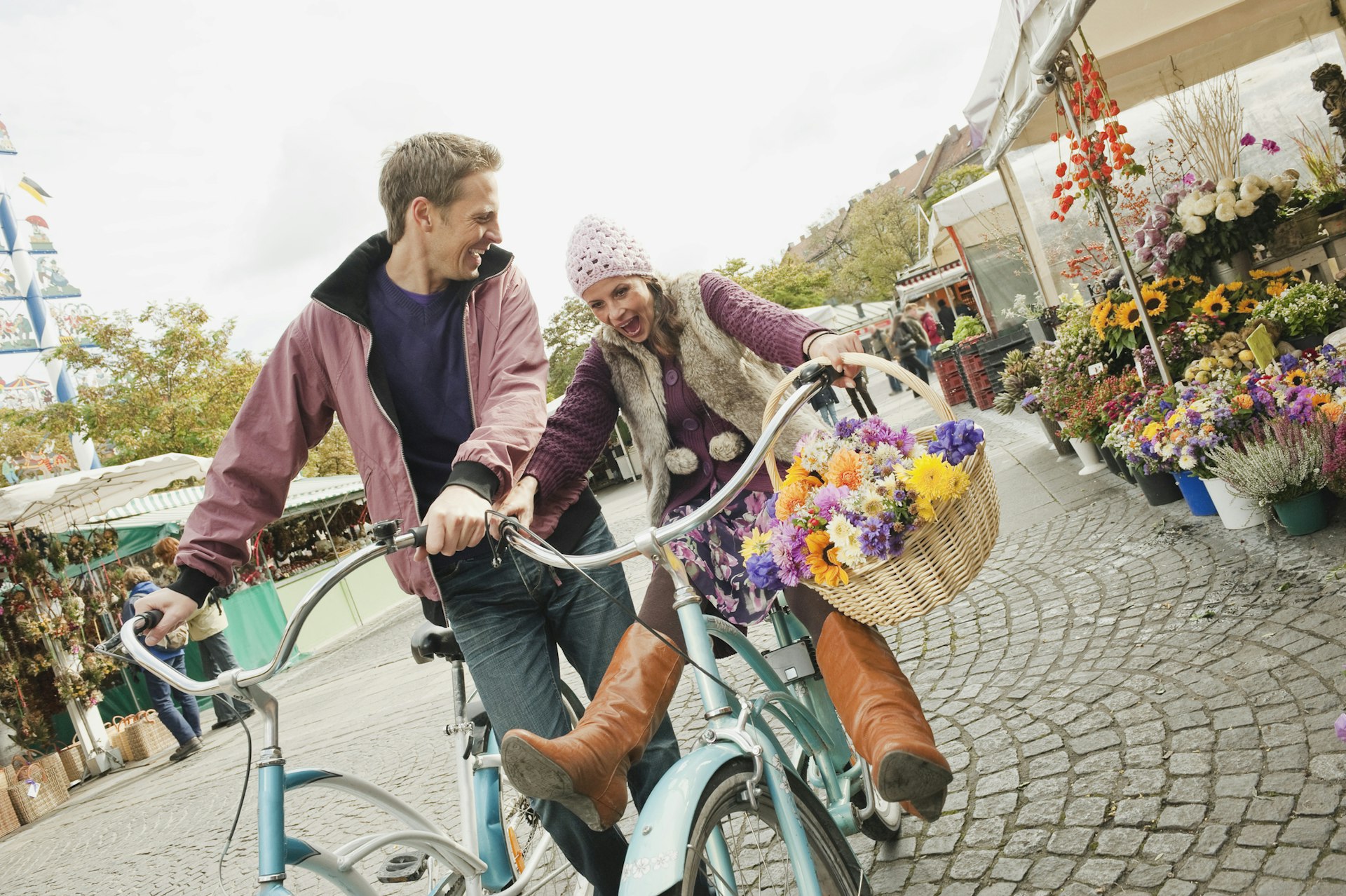 A couple are cycling side by side and laughing in Munich