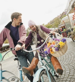 Germany, Bavaria, Munich, Viktualienmarkt, Couple with bicycles, laughing, portrait 
