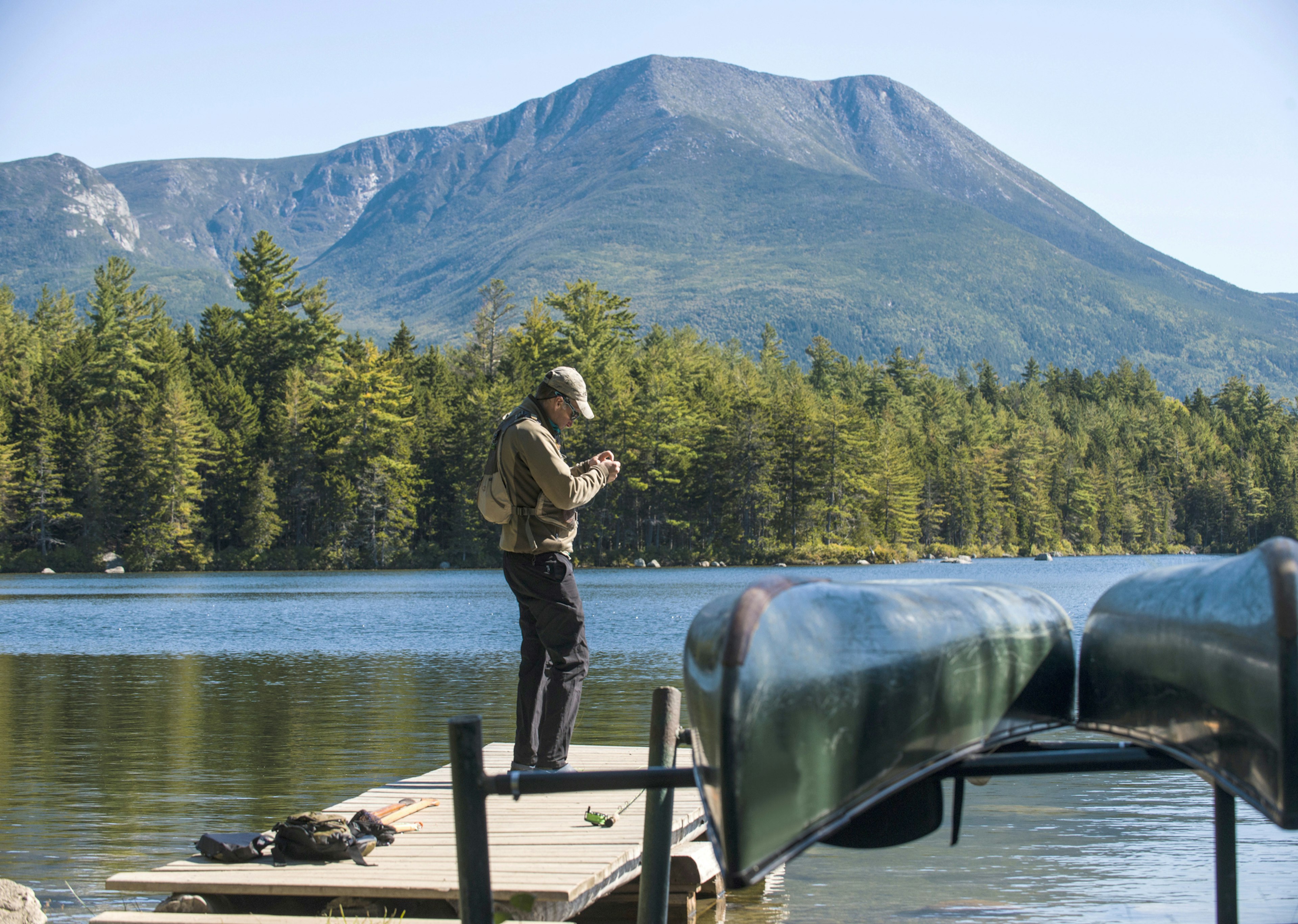 Fly Fisherman getting his gear ready on the dock at Kidney Pond in Baxter State Park, Maine 