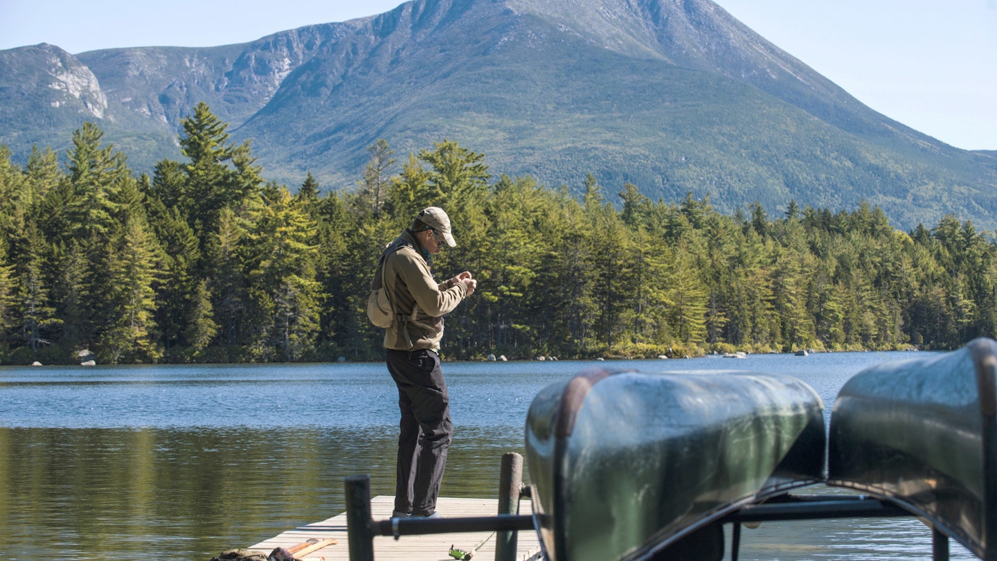 Fly Fisherman getting his gear ready on the dock at Kidney Pond in Baxter State Park, Maine 