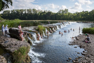 Kuldiga, Latvia - August 10, 2014: People are swimming by the waterfall. It's the longest waterfall in Europe.