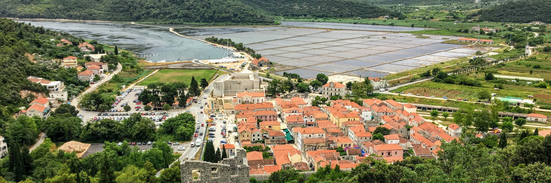 Ston, Croatia - July 9th, 2019: A group of tourists walking down along the the Walls of Ston, towards the ancient town of Ston, Croatia below.