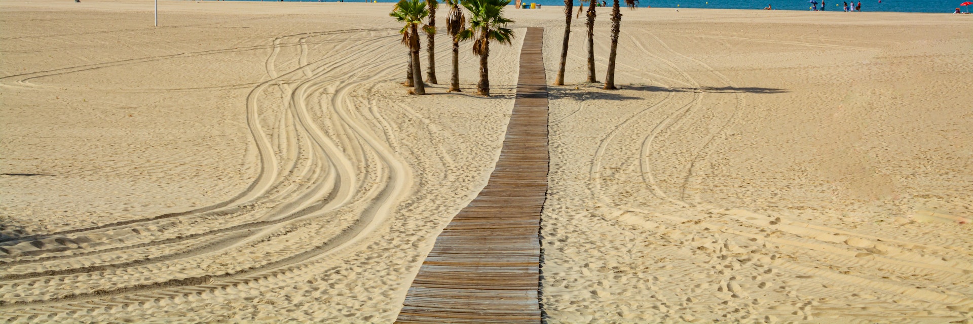 Beautiful local sandy beach with palm trees Playa de la Puntilla on Atlantic ocean in El Puerto de Santa-Maria, Andalusia, Spain