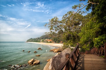Stunning nature of Kuantan. Best Kuantan beach resorts famous for pristine nature. Coastline with tropic nature plants sand beaches. Bridge or wooden pier at sea lagoon with rocks and waves.