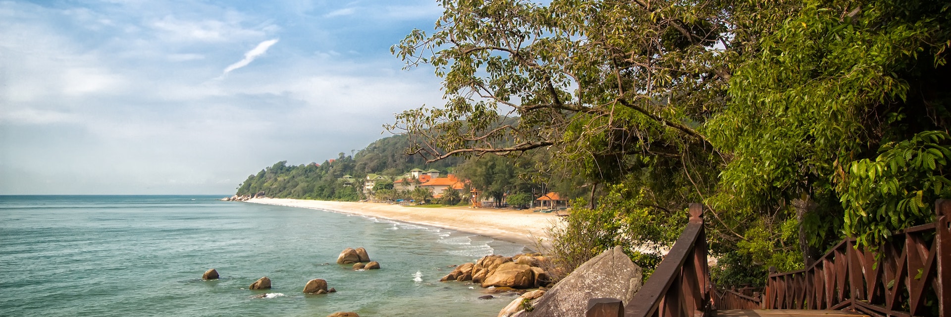 Stunning nature of Kuantan. Best Kuantan beach resorts famous for pristine nature. Coastline with tropic nature plants sand beaches. Bridge or wooden pier at sea lagoon with rocks and waves.