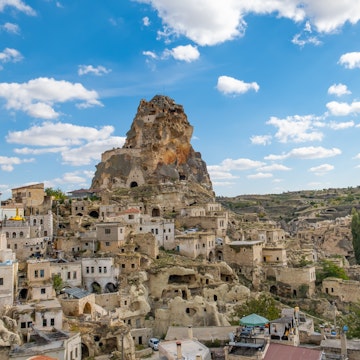 Ortahisar castle or central castle and fairy chimneys in Cappadocia, Turkey at sunset. Ortahisar Castle and traditional houses carved stone. Cave houses in fairy chimneys.