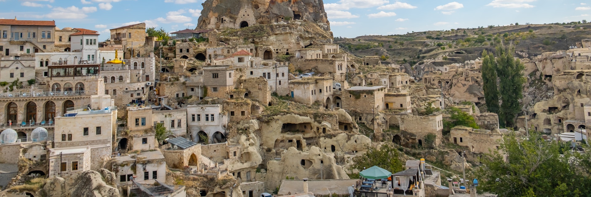 Ortahisar castle or central castle and fairy chimneys in Cappadocia, Turkey at sunset. Ortahisar Castle and traditional houses carved stone. Cave houses in fairy chimneys.