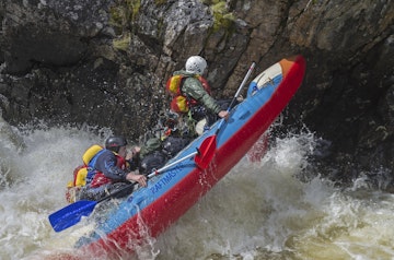 Vuosnayoki River, Murmansk Region, Russia - June 9, 2015: People on sport catamaran in hard and dangerous situation when  overcoming a difficult rarids on Vuosnayoki river, the border of the Murmansk region and Karelia, Russia.