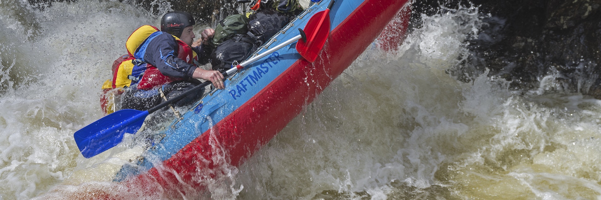 Vuosnayoki River, Murmansk Region, Russia - June 9, 2015: People on sport catamaran in hard and dangerous situation when  overcoming a difficult rarids on Vuosnayoki river, the border of the Murmansk region and Karelia, Russia.